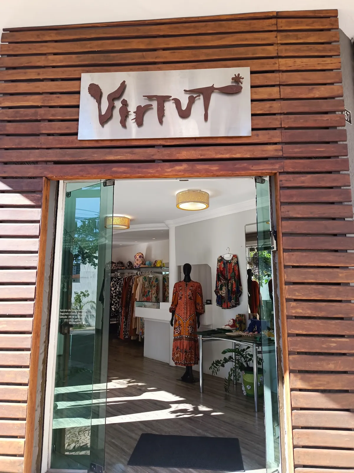 Entrada da Virtut, com o letreiro na fachada de madeira e a porta de vidro aberta